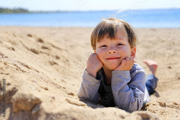 Obraz Ein dreijähriger Junge liegt im Sand