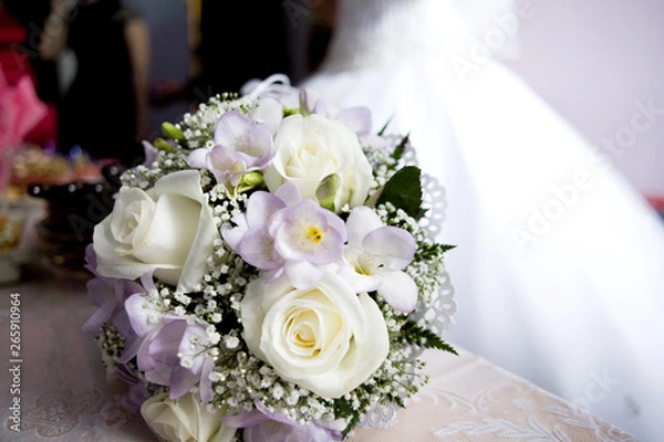 Obraz White rose buds in combination with a gray freesia and a sprig of gypsophila in a bouquet of the bride on a blurred background of a wedding dress.