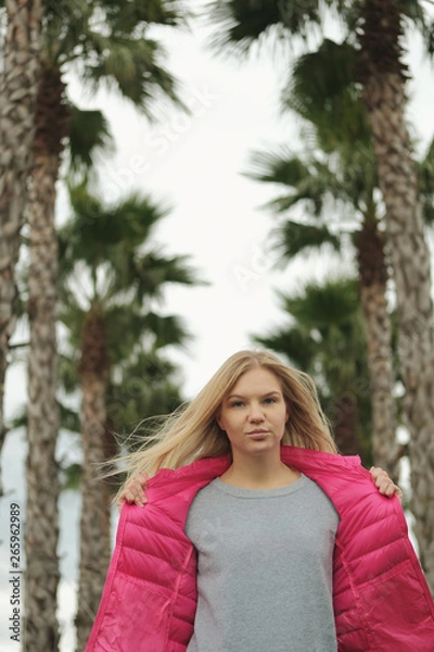 Fototapeta Portrait of beautiful blond girl posing for photo at the park with palm tree
