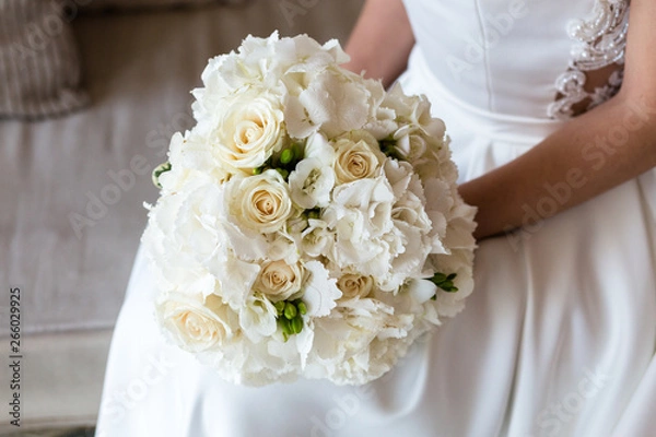 Obraz Exquisite bridal bouquet of white roses, hydrangeas and freesia in the hands of an unrecognizable bride