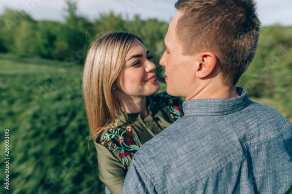 Fototapeta Loving guy and girl kisses in nature.concept of love story outdoor.Lovers Walking in spring park.stylish couple in love hugging on a walk in spring
