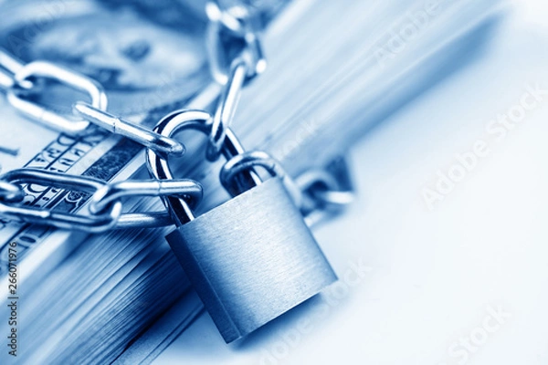 Fototapeta Business safety or financial protection or restriction access. Heap of money in chain with padlock isolated on white