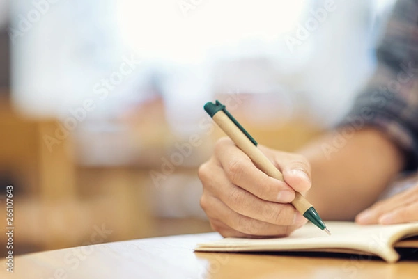 Fototapeta Close-up of businessman hand with pen writing on notebook. Business and education concept.