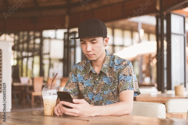 Fototapeta A Man Checking his Smartphone at coffee shop in vintage style