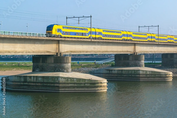 Fototapeta Dutch passenger train passing a bridge