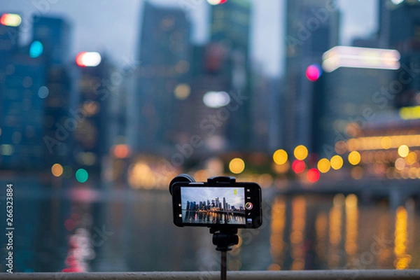 Fototapeta Smart phone for capture a photo on tripod .View of screen making photo on mobile phone camera of Marina ,Singapore