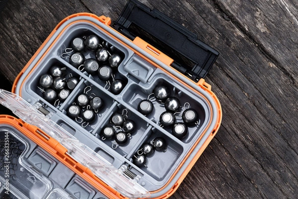 Fototapeta Fishing box filled with tungsten sinkers on the wooden table.
