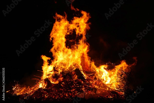 Obraz Large bonfire, burning and glowing with soft flames, sparkles flying agains the dark sky. Glowing wood silhouettes. Walpurgis night, traditional witch burning and spring welcoming ritual. 30 April.
