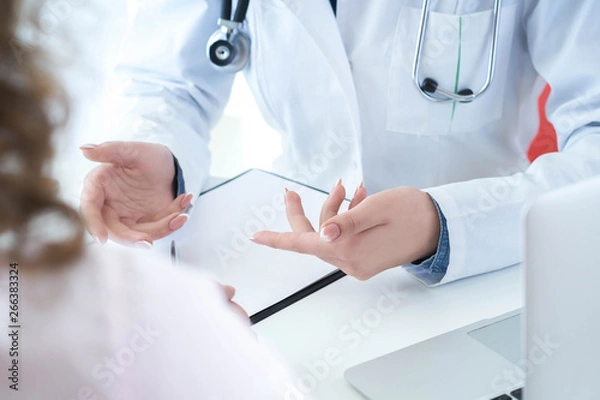 Fototapeta Patient listening intently to a female doctor explaining patient symptoms or asking a question as they discuss together in a consultation.