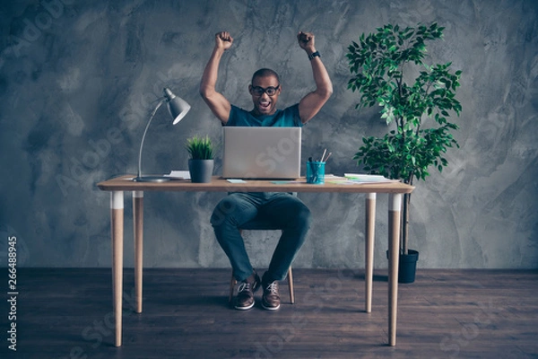 Fototapeta Full length body size photo amazing he him his handsome first earned salary notebook table lamp light green plant reliable person wear specs blue t-shirt pants sit chair indoors workstation office