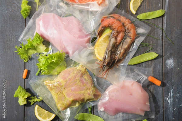 Fototapeta Sous Vide cooking concept. Vacuum packed ingredients arranged on wooden dyed background.