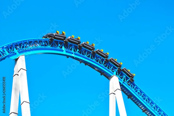 Fototapeta Blue spooky scary roller coaster fast riding with loop and yellow seats in the amusement park in holiday weekend. Empty roller coaster without people