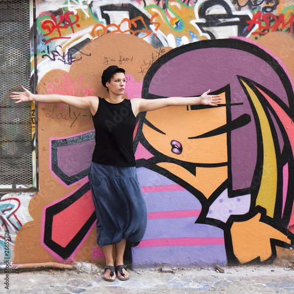 Obraz Jeune femme s'étirant devant un mur couvert de graffitis