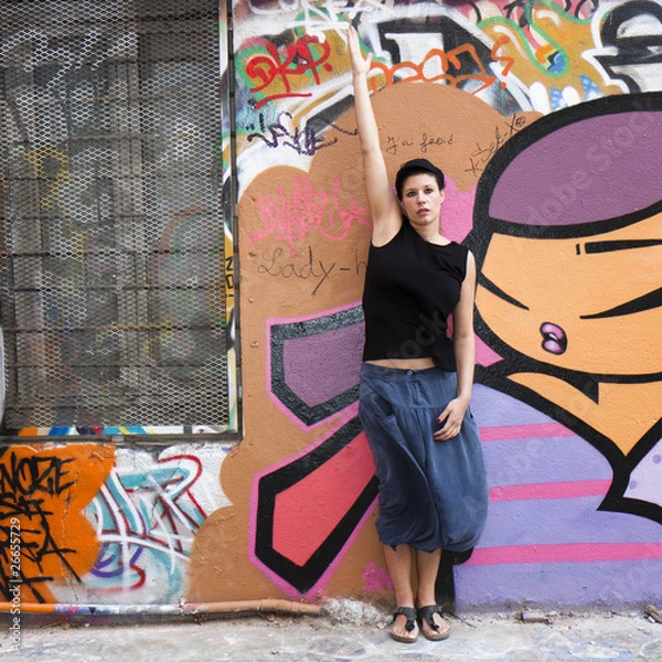 Obraz Jeune femme levant un bras devant un graffiti