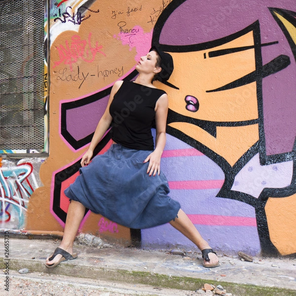 Obraz Jeune femme dansant devant un mur couvert de graffitis