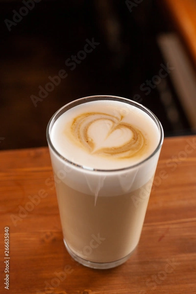 Fototapeta Latte in a glass with latte art on a milk froth