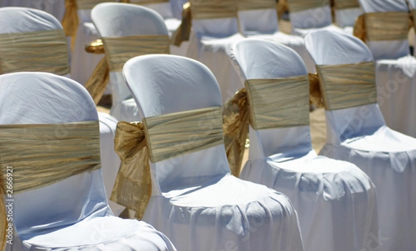 Obraz white chairs with gold ribbon at a beach wedding