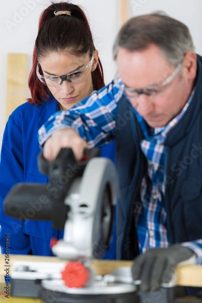 Fototapeta female student in carpentry class using circular saw