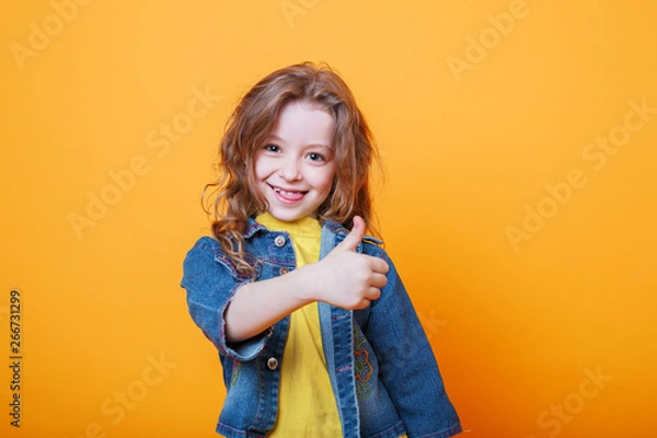 Obraz Cute little girl showing thumbs up on orange background