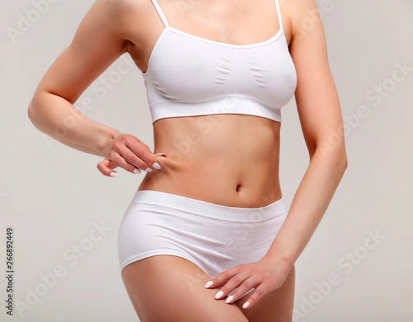 Fototapeta Woman pinches fat on her belly, closeup shot