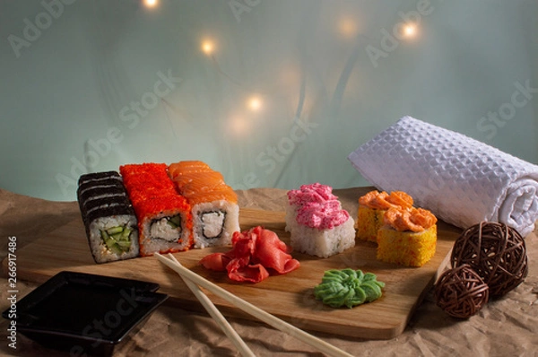 Fototapeta sushi in the sun on a wooden board with a beautiful background