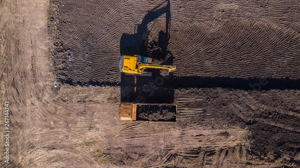 Fototapeta Aerial construction - top down view of an excavator and truck working on a construction site