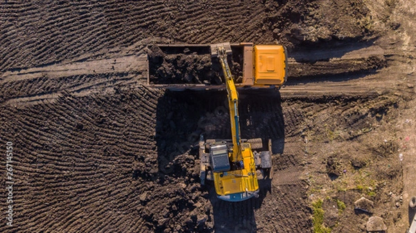 Fototapeta Aerial construction - top down view of an excavator and truck working on a construction site