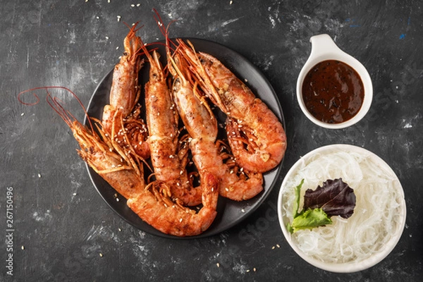 Obraz Fried grilled prawns with rice noodle, sauce and lettuce, dark background,copy space