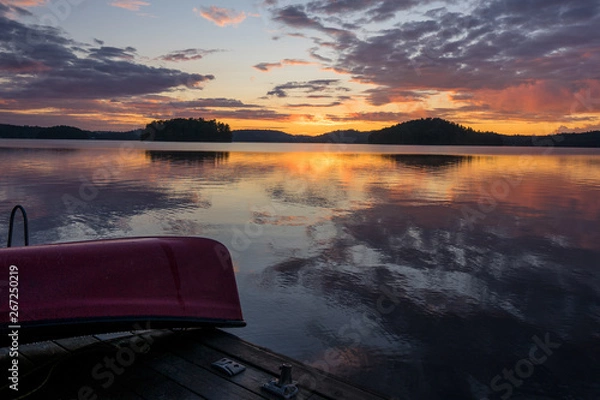 Fototapeta canoe and reflection in water at sunset 