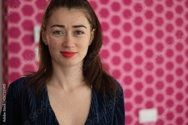Fototapeta Beautiful young woman looking into the camera standing in front of a pink background