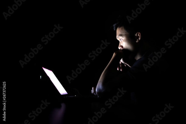 Fototapeta Lonely developer thinking solution with laptop at night in the dark room