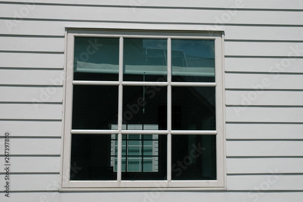 Fototapeta White 9 pane window with reflections in clapboard siding