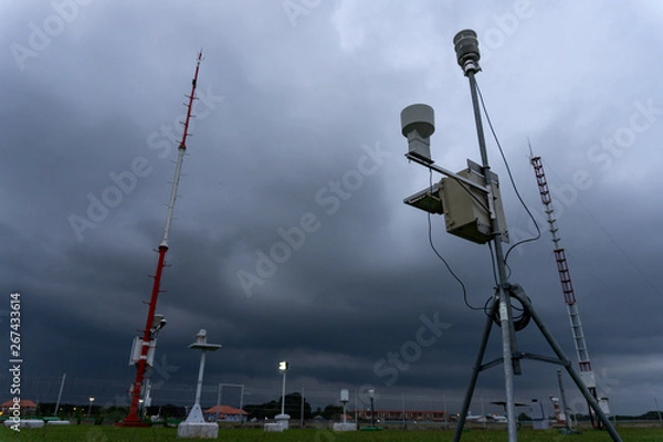 Fototapeta BADUNG,BALI-APRIL 11 2019: a Portable Automatic Weather Station at Ngurah Rai airport under the scary dark Cumulonimbus clouds at Ngurah Rai International Airport