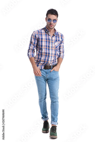 Fototapeta Confident guy walking forward and wearing sunglasses