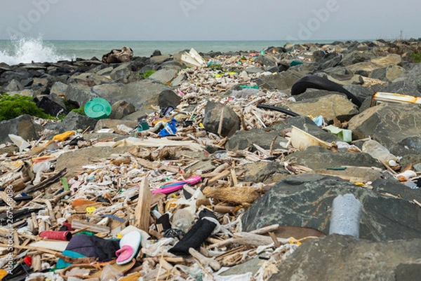 Fototapeta Spilled garbage on the beach near the big city. Empty used dirty plastic bottles and other garbage. Environmental pollution. Ecological problem.