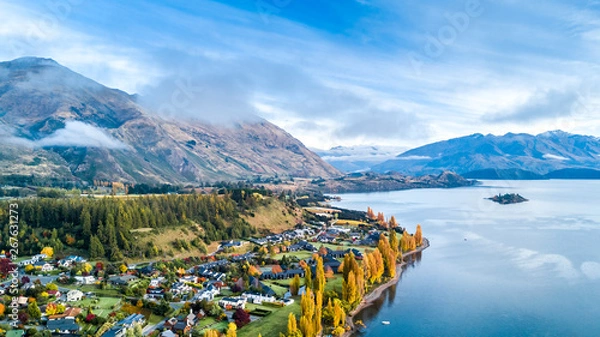 Obraz Small town surrounded by yellow autumn trees on a shore of pristine lake with mountains on the background. Wanaka, Otago, South Island, New Zealand