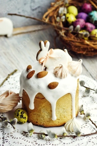 Obraz Easter cake in the form of a rabbit on a table, a table decorated with rabbits, against the background of a basket with multi-colored quail eggs,