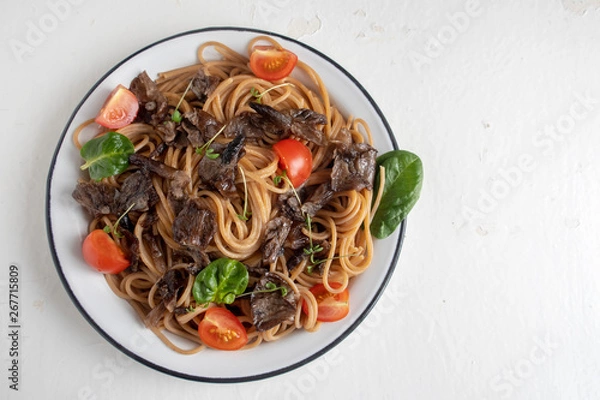 Obraz Brown buckwheat spaghetti with mushrooms, tomato and cress lettuce and spinach on a light wooden background, healthy food concept. Close-up and copy space. Top view.