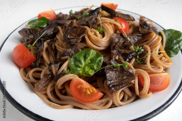Obraz Brown buckwheat spaghetti with mushrooms, tomato and watercress salad on a light wooden background, healthy food concept. Close-up.