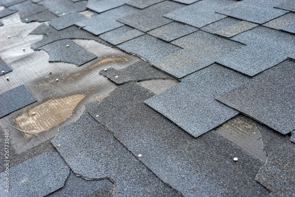 Fototapeta Сlose up view of bitumen shingles roof damage that needs repair.