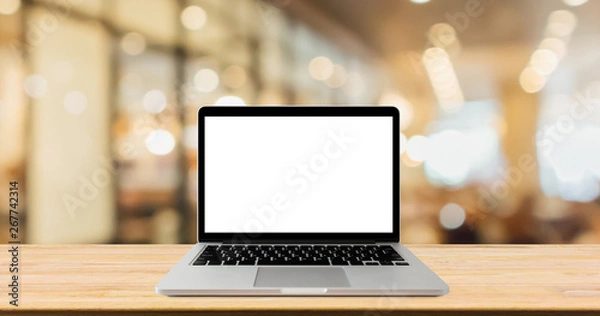 Fototapeta Blank screen laptop computer on wood table top with blur cafe restaurant with abstract bokeh light defocused background