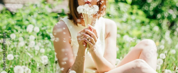 Fototapeta  woman holding dandelions.Spring mood. Free space for text. Walk in the summer park.