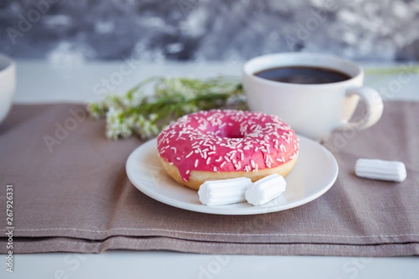 Fototapeta Glazed donut with black coffee and marshmallows. Pink tasty donut on a table. Morning breakfast.