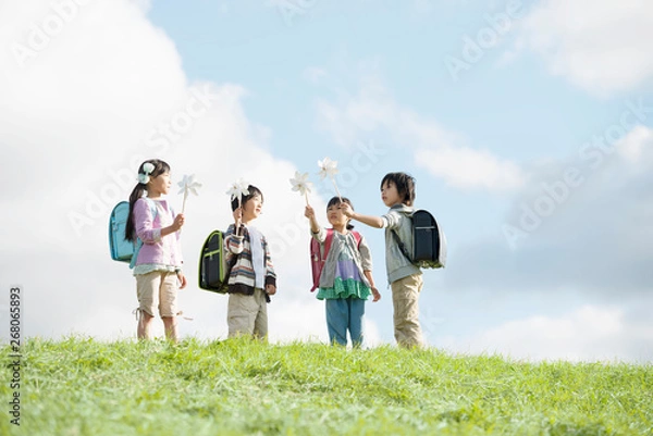 Fototapeta 草原で風車を持つ小学生