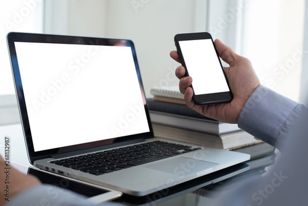 Fototapeta Mockup image of businessman using smartphone working on laptop