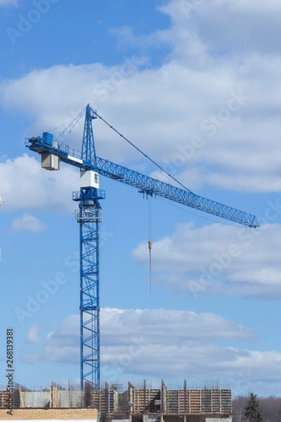 Fototapeta Construction crane unfinished building on background of cloudy sky. Construction of house, office center