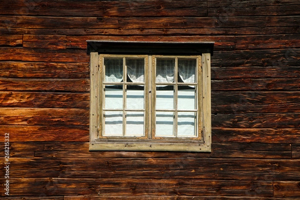 Fototapeta A detail of the planks of the scandinavian wooden house. The color of the house is old and looks shabby. One window can be seen. 