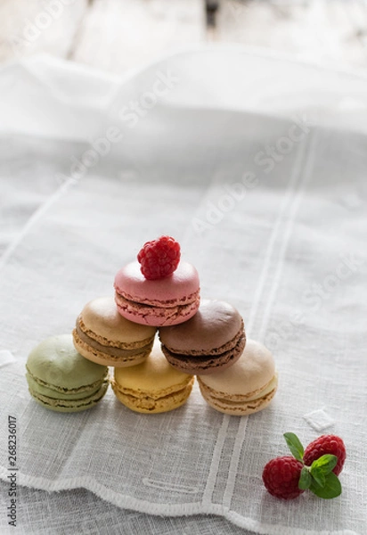 Obraz Macarons on white background and rustic wooden table