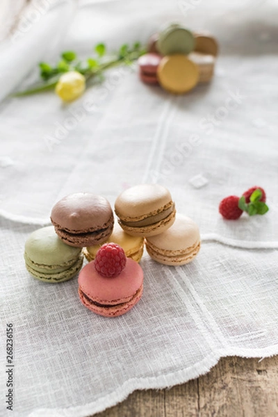 Obraz Macarons on white background and rustic wooden table