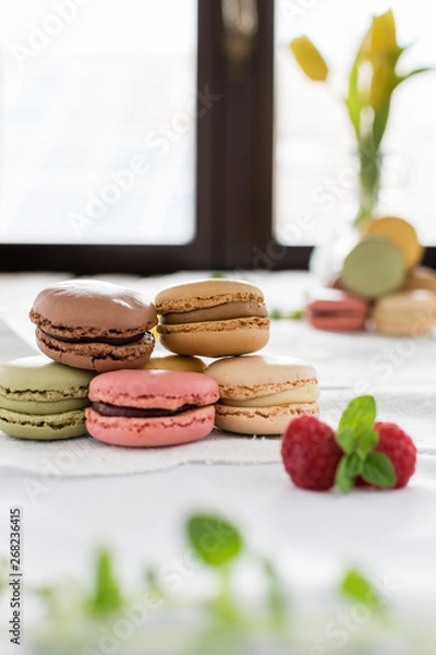 Obraz Macarons on white background and rustic wooden table